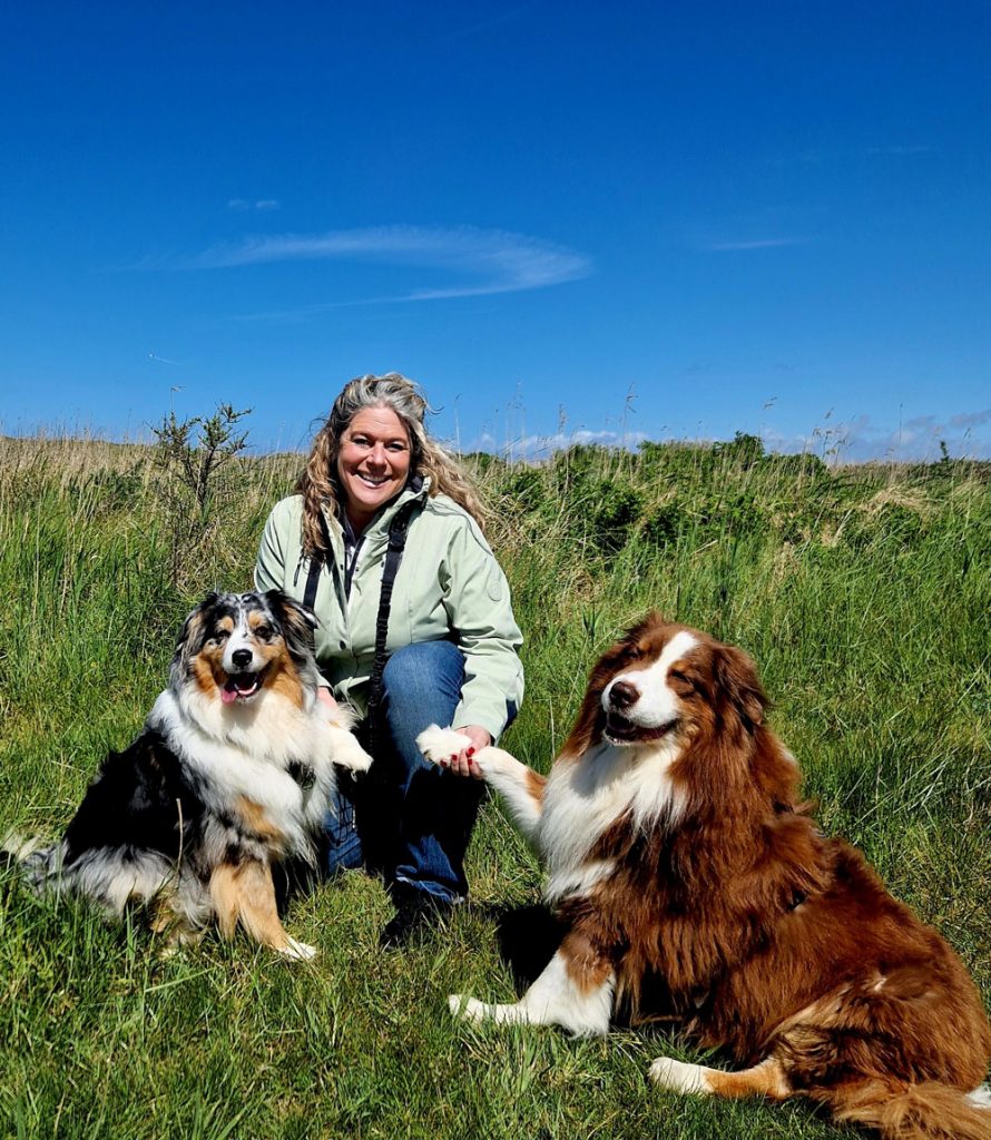 Cordula Ahlers mit ihrem zwei Hunde im Gras in Dänemark